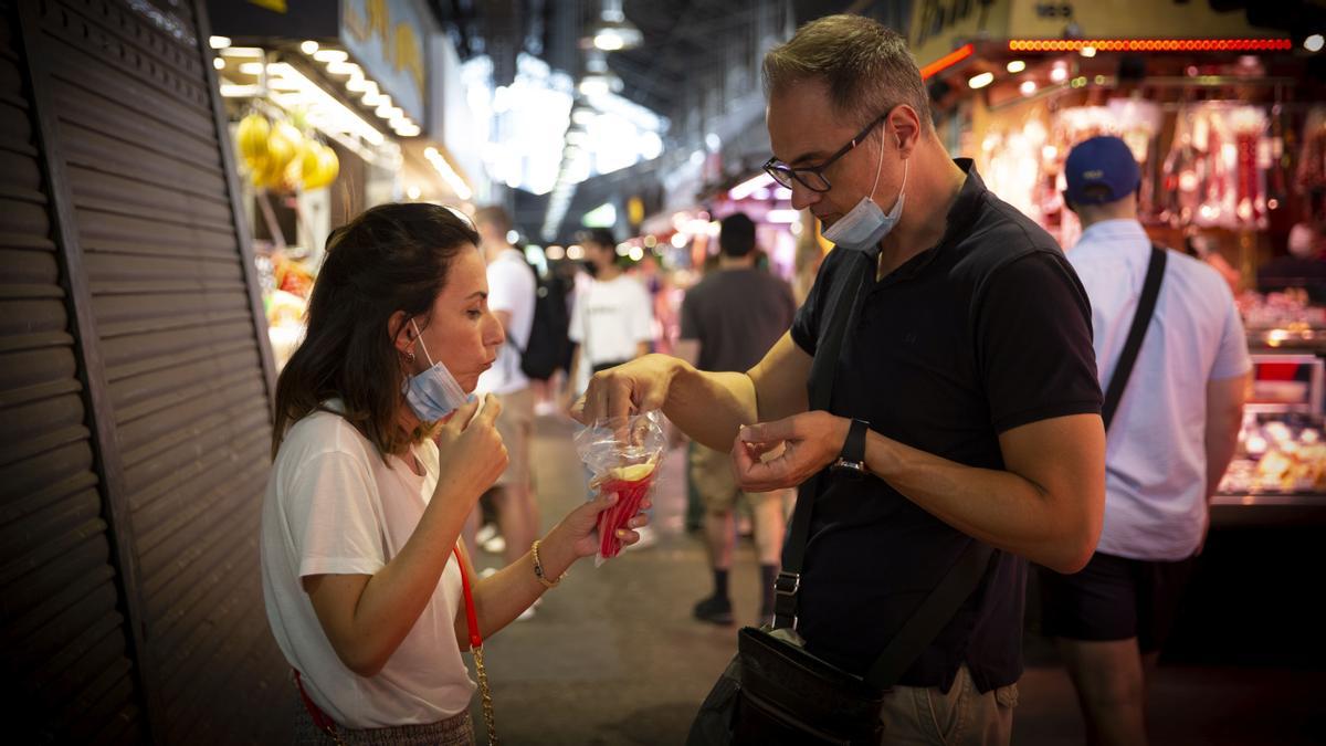 Los turistas comen tapas de jamón y queso compradas en el mercado, las paradas tradicionales conviven con las nuevas peticiones del turismo