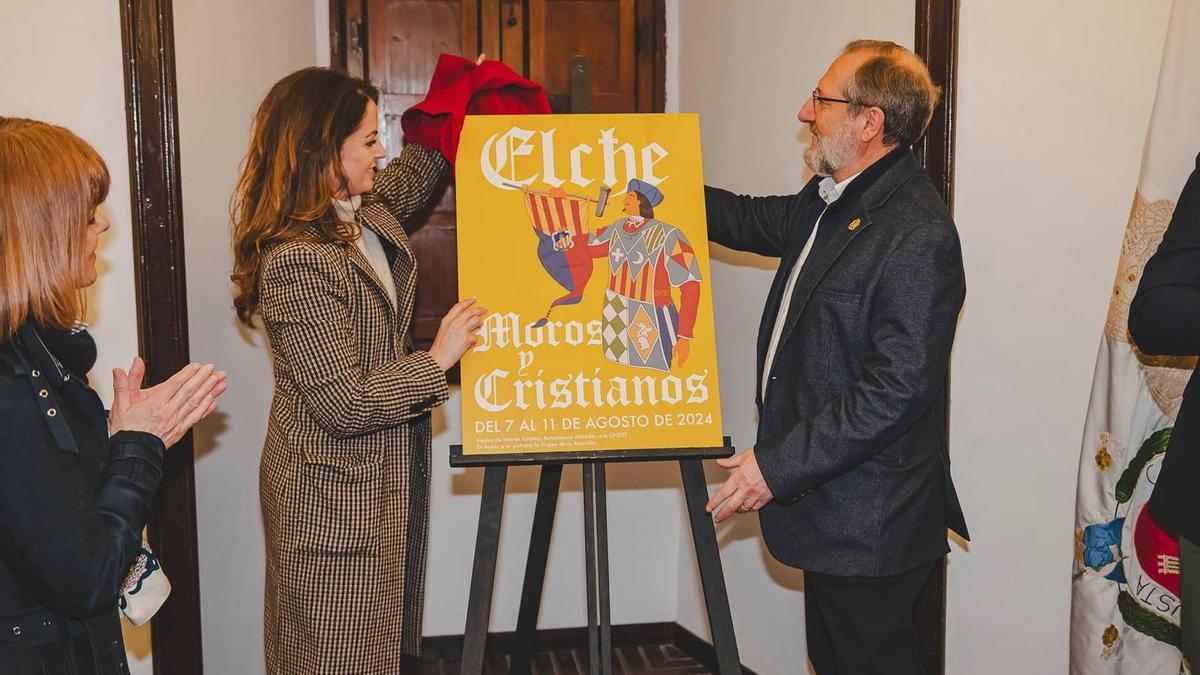 El presidente de los Moros y Cristianos de Elche, Julián Fernández, desvela el cartel junto a la edil de Festejos, Inma Mora, este miércoles