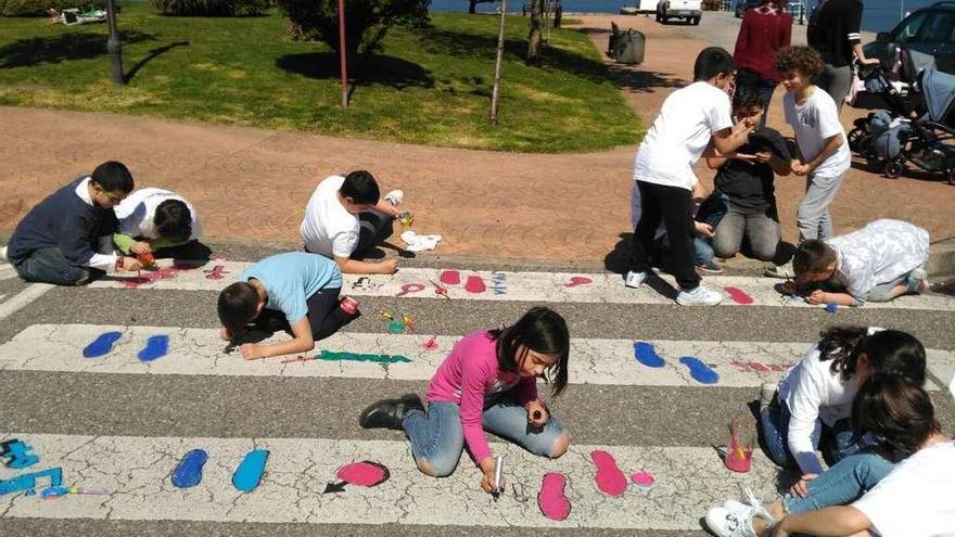 Unos escolares pintan un paso de peatones en el paseo de Cardona, ayer, en Chapela. // FdV