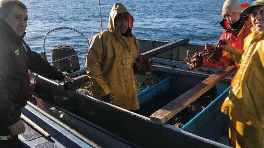 Un vigilante de la cofradía charla con los tripulantes del barco &quot;Laverca&quot; en plena faena. // Muñiz