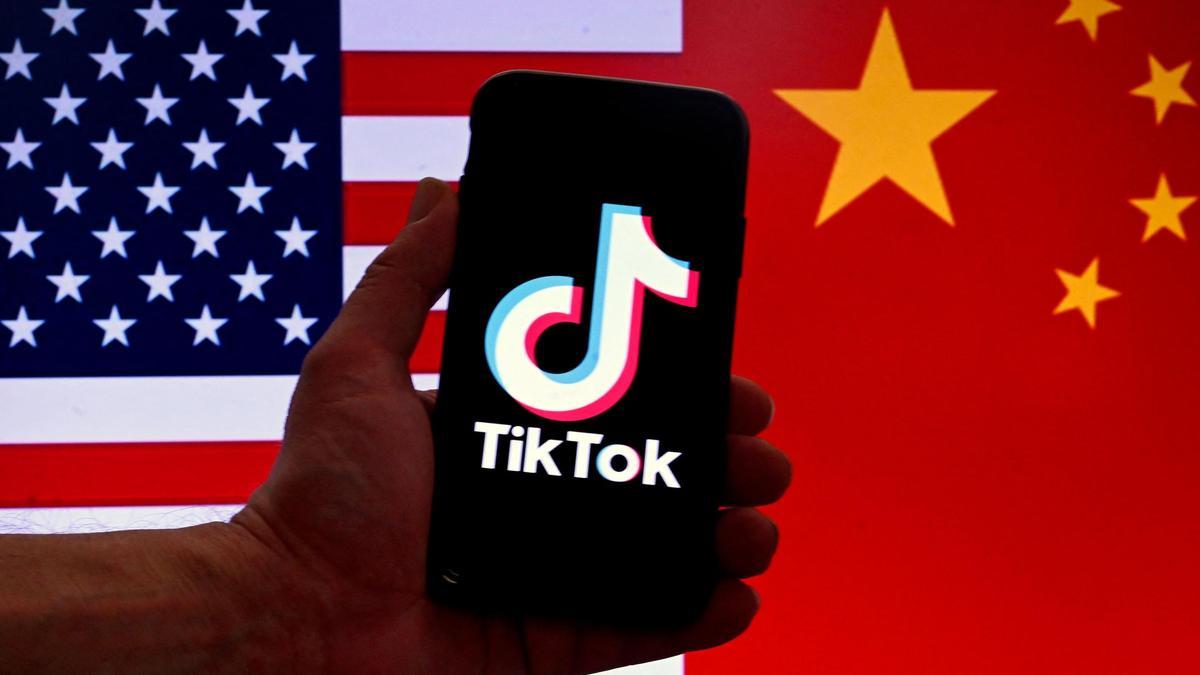 El logo de TikTok frente a una pantalla con las banderas de EEUU y China.
