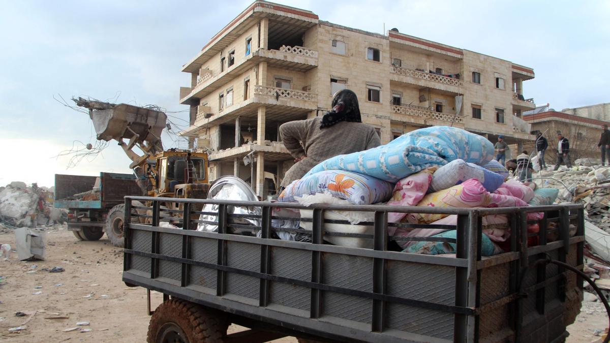 Una mujer se sienta sobre los artículos rescatados de un edificio destruido en la ciudad de Jindayris, Siria.  