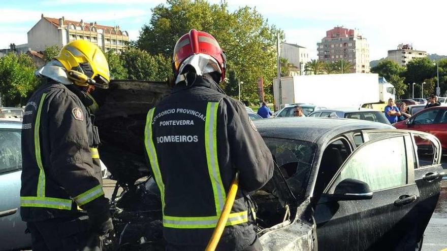 Dos bomberos terminan de apagar el fuego declarado en un coche en Vilagarcía. // Iñaki Abella