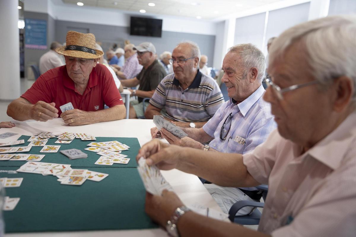 Un grupo de personas jubiladas juegan al dominó y a las cartas en el Casal de la Gent Gran Bellvitge-LErmita