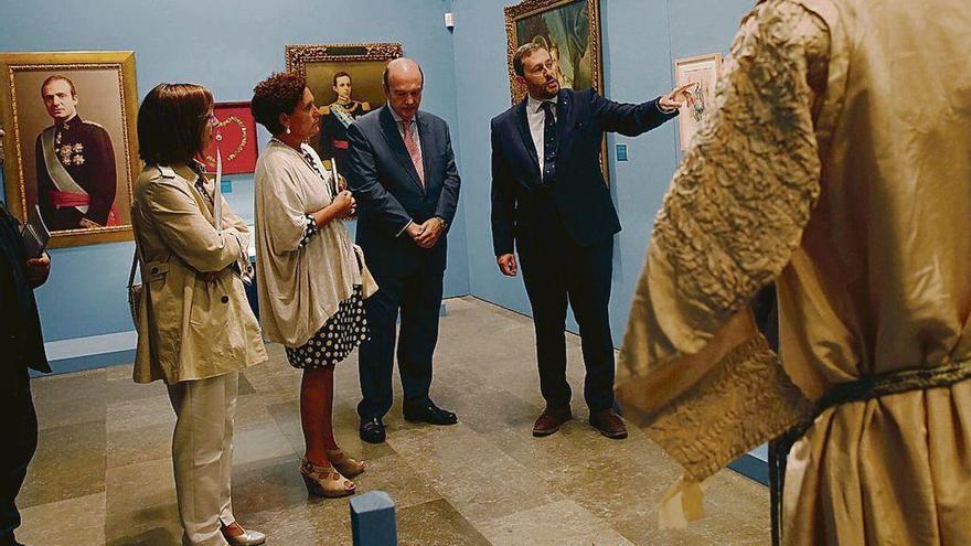 Arriba, Alfonso Ceballos-Escalera explica junto a Rafael Feria uno de los objetos de la exposición. Abajo, retrato de Felipe VI con los atributos de la Real Orden de Carlos III y asistentes al acto de presentación de la muestra, que se inaugura hoy.