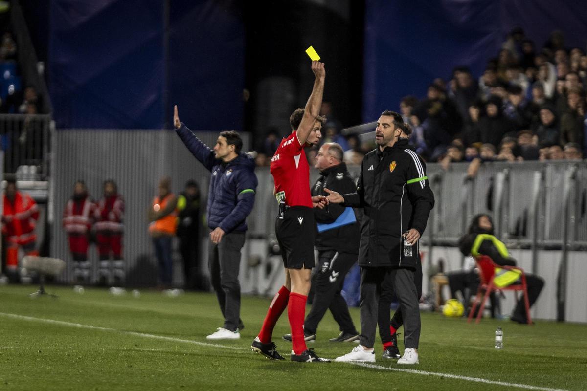 El colegiado, mostrando tarjeta amarilla al banquillo zaragocista ante el lamento de Sellés