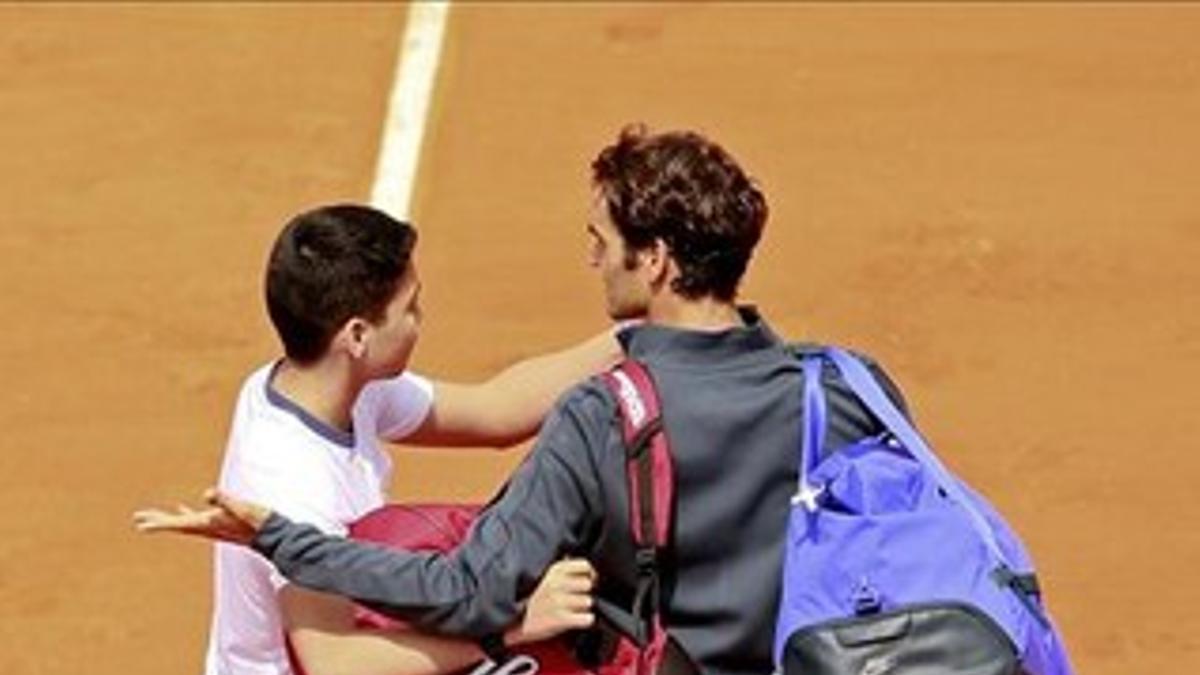 Un espectador intenta hacerse una foto con Federer en la pista después de que el suizo derrotara a Falla en la primera ronda de Roland Garros.