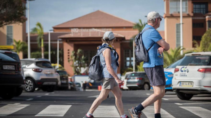 Una pareja de turistas extranjeros mira hacia la entrada del hotel del sur de Tenerife que se mantuvo en cuarentena por el coronavirus.
