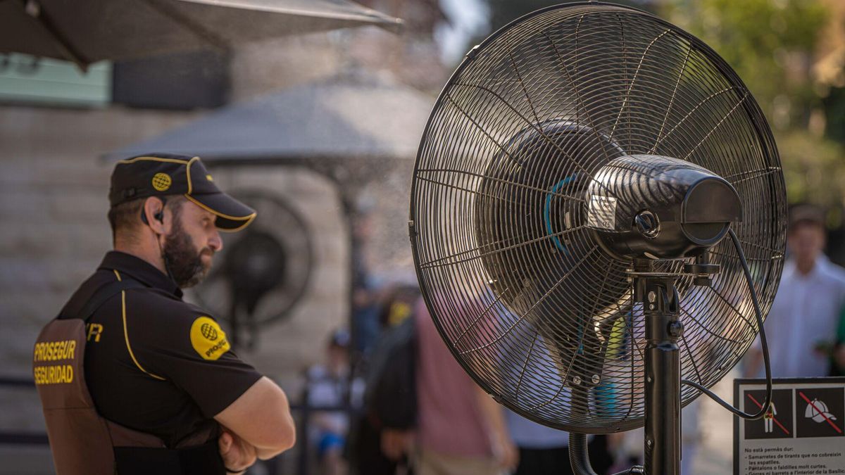 Un vigilante de seguridad se refresca ante un ventilador colocado durante la ola de calor en Barcelona.