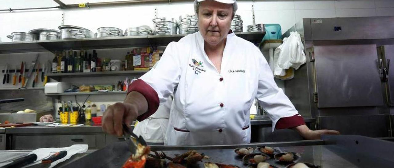 Lola Sánchez prepara unos mariscos a la plancha en la cocina de la sidrería Yumay, en Villalegre.