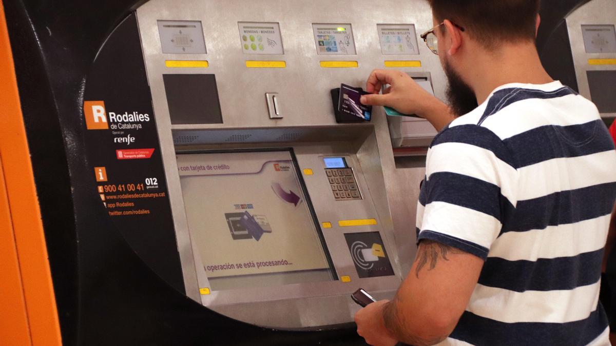 Un noi utilitzant una màquina d'autovenda de Rodalies el primer dia en vigor dels abonaments gratuïts