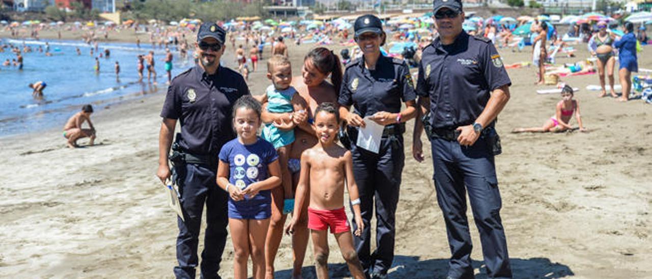 Los tres agentes, con algunos de los niños con las pulseras, ayer, en Melenara.