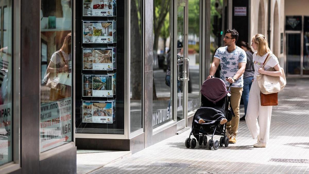 Dos personas observan los anuncios de viviendas en venta en una inmobiliaria.