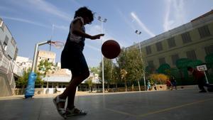 Una niña jugando a baloncesto en el patio del colegio.