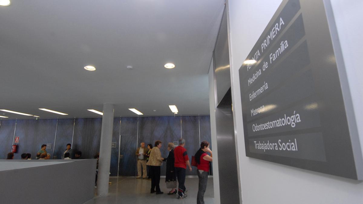 Pacientes en el entorno del centro de salud Mieres Sur, con el cartel ya pegado a la entrada.