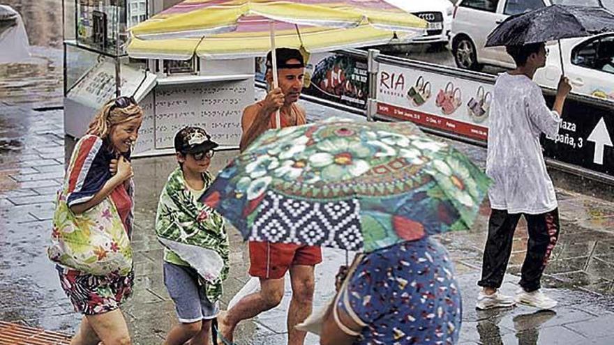 Un grupo de personas se resguarda como puede de la lluvia en Palma.