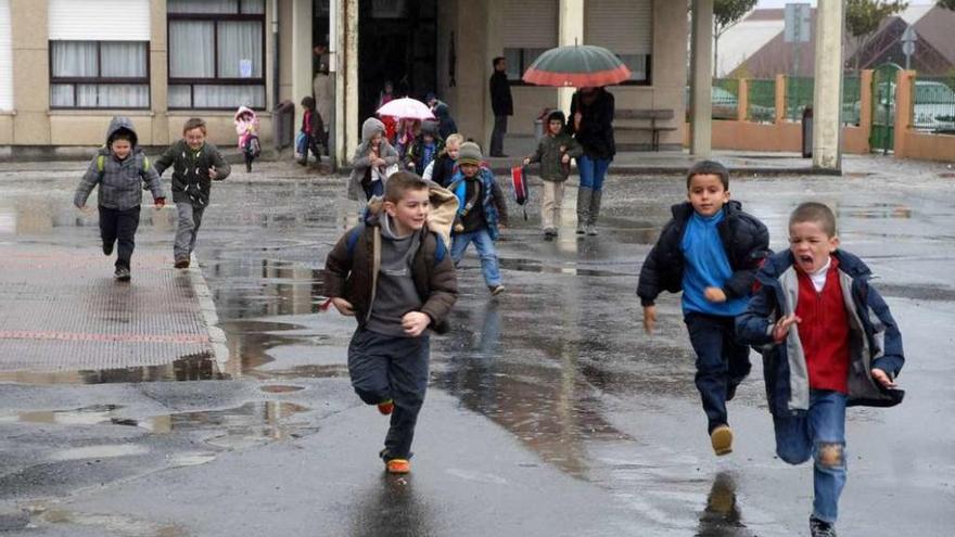 Un grupo de niños sale corriendo del edificio de Infantil sin protección para la lluvia. // Bernabé/Javier Lalín