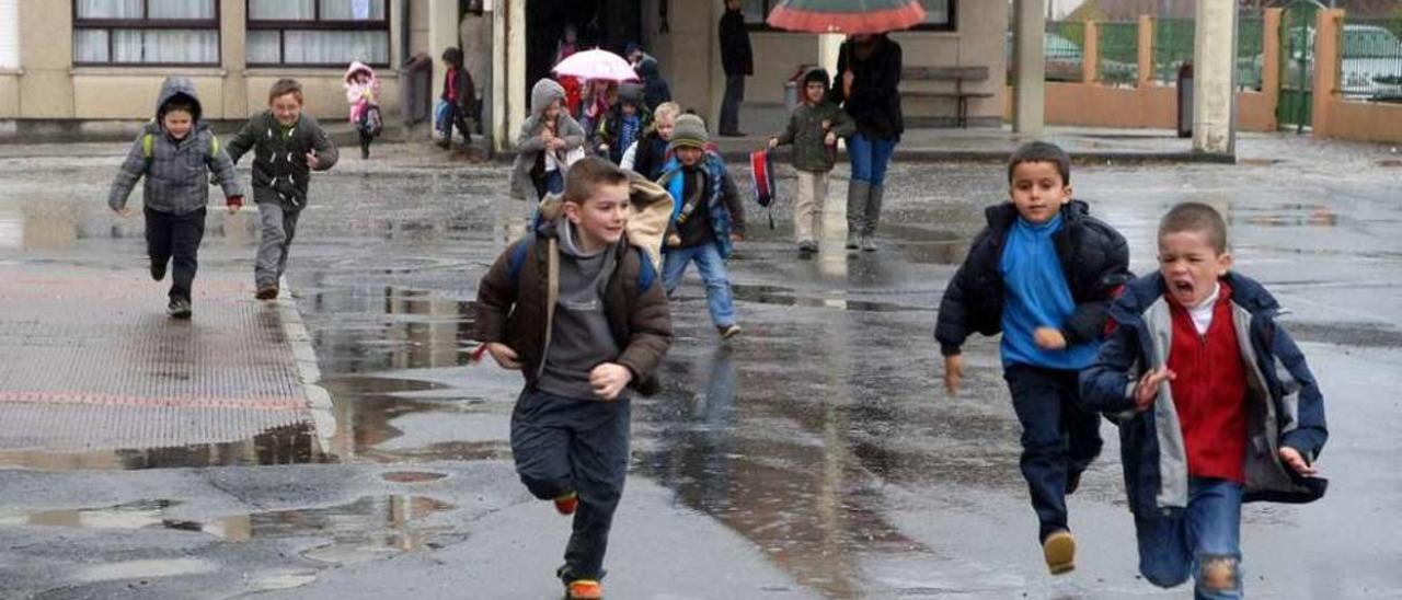 Un grupo de niños sale corriendo del edificio de Infantil sin protección para la lluvia. // Bernabé/Javier Lalín