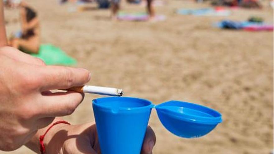 Una persona utiliza un cenicero en una playa de València. | F. BUSTAMANTE