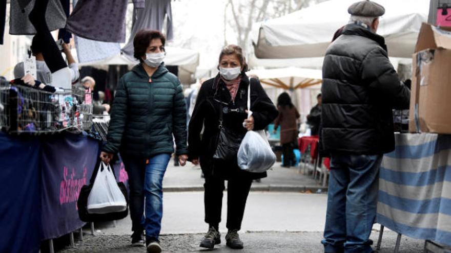 Dos mujeres pasean con mascarilla por el mercado de Milán.