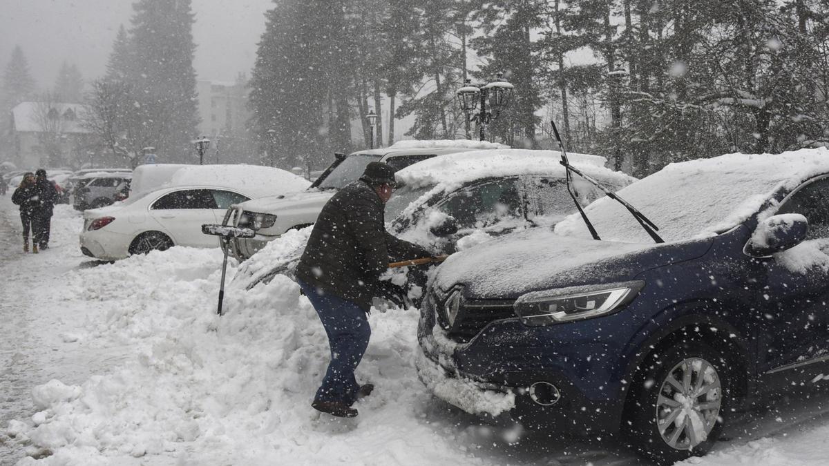 Turistas y habitantes de Canfranc (Huesca) quitan la nieve de sus coches con palas debido a la nieve caída.