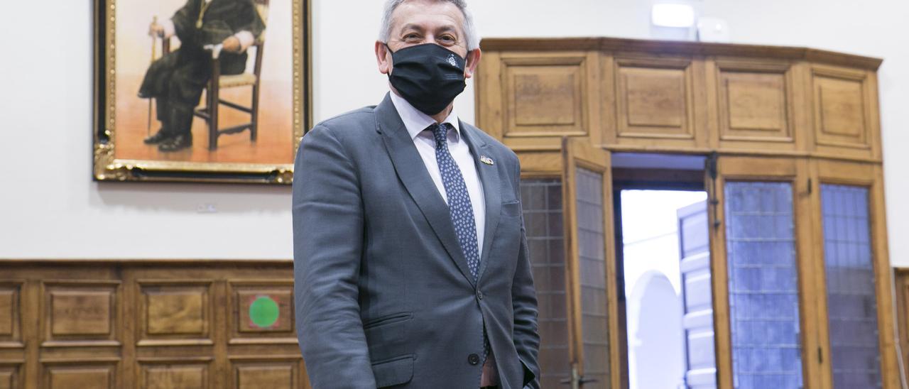 Santiago García Granda posa delante de su retrato en el Aula Magna de la Universidad