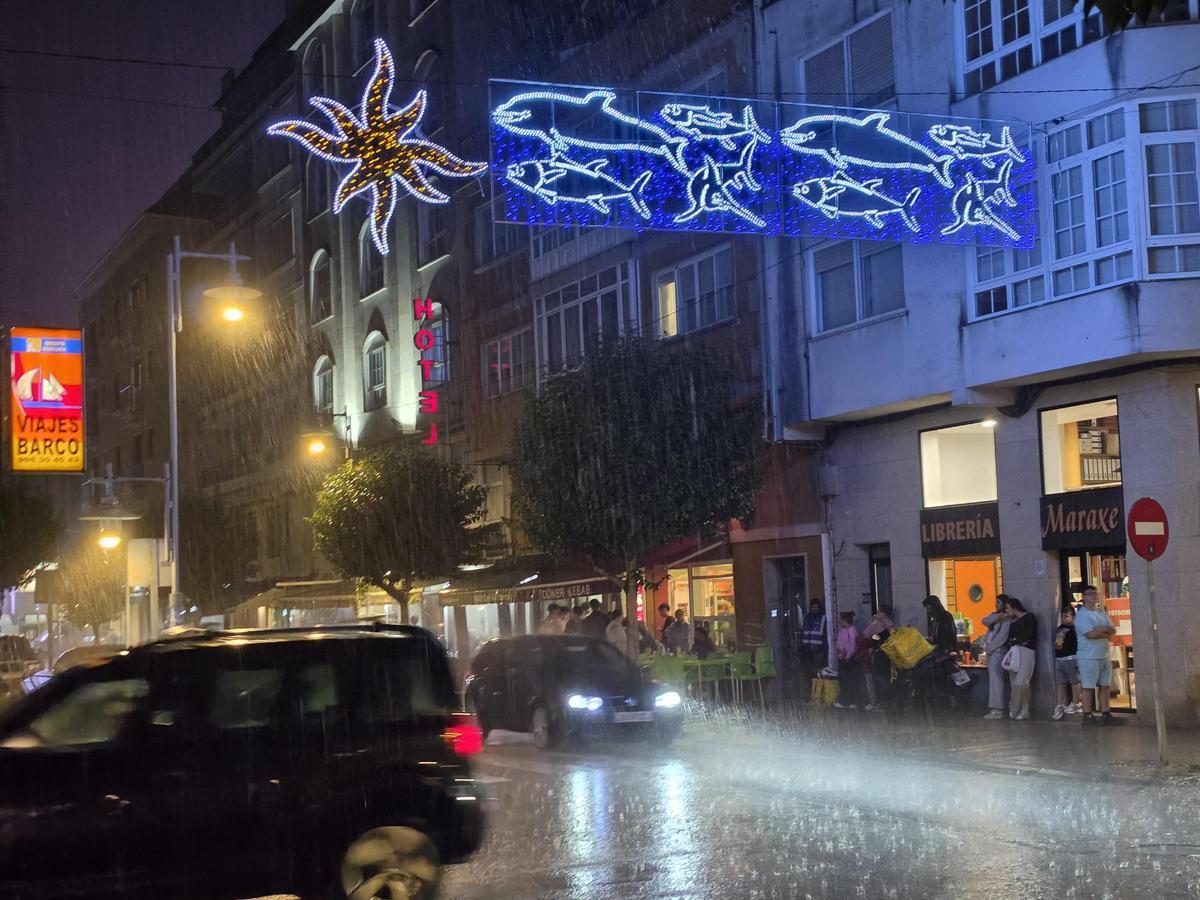 Vecinos refugiándose de la lluvia, la noche del domingo, en la Avenida de Marín.