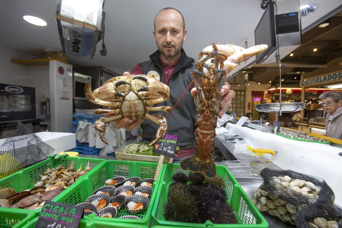 Un vendedor del Mercado Central de Alicante sostiene un centollo y un bogavante.