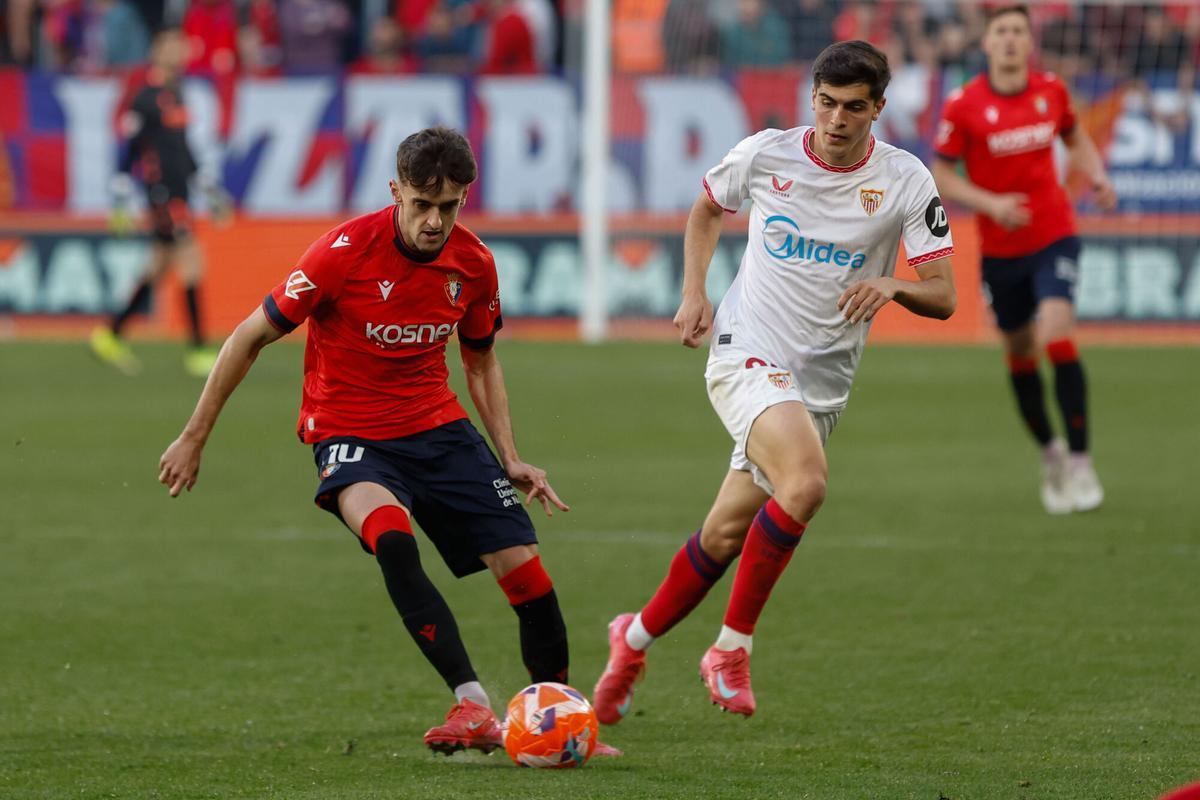 El centrocampista del Osasuna Aimar Oroz (i) se escapa de Juanlu, del Sevilla, durante el partido de la jornada 33 de LaLiga EA Sports entre el Atlético Osasuna y el Sevilla FC, hoy jueves en el estadio de El Sadar, en Pamplona.