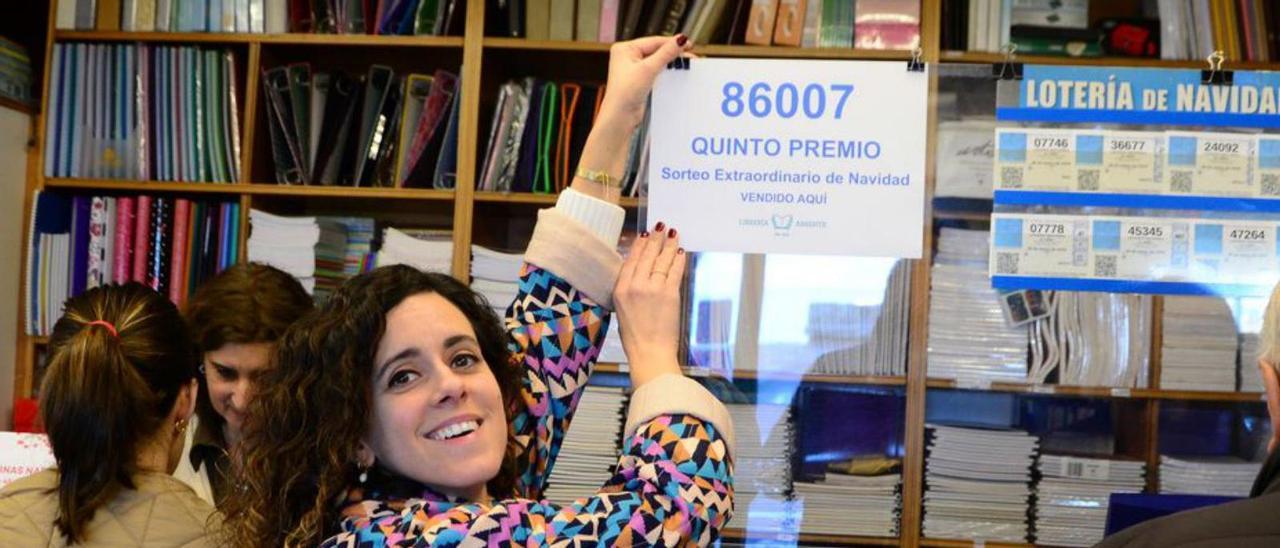 Elena Bangueses, de la Librería Abrente, ayer con un cartel del quinto premio repartido con el número 86.007.
