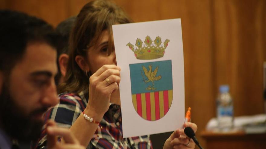 La edil de Festividades, Mariola Rocamora, muestra en el pleno la imagen del nuevo escudo de Orihuela