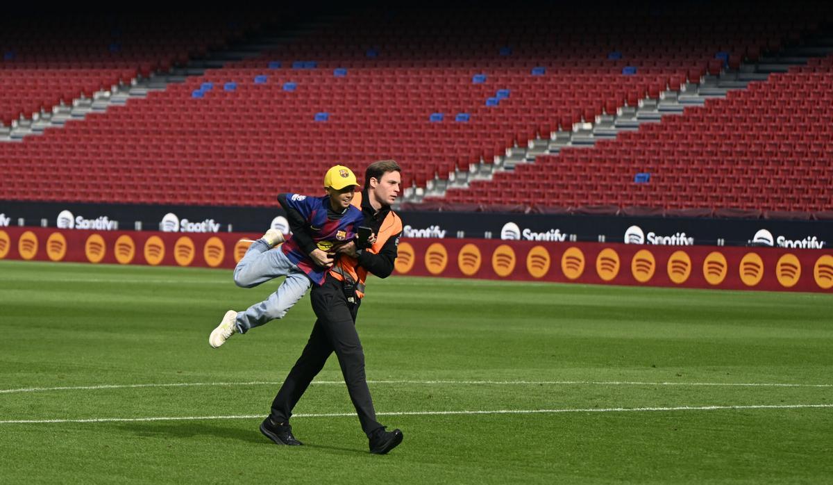 Barcelona. 07.11.2025.  Deportes.  Un miembro de seguridad bloquea a un chaval,  que quería acercarse a los jugadores, sobre el césped ante los casi 22.000 aficionados que han presenciado desde la grada el entrenamiento de los jugadores del Barça en el Spotify Camp Nou en el primer test con asistencia de público en el estadio. Fotografía de Jordi Cotrina