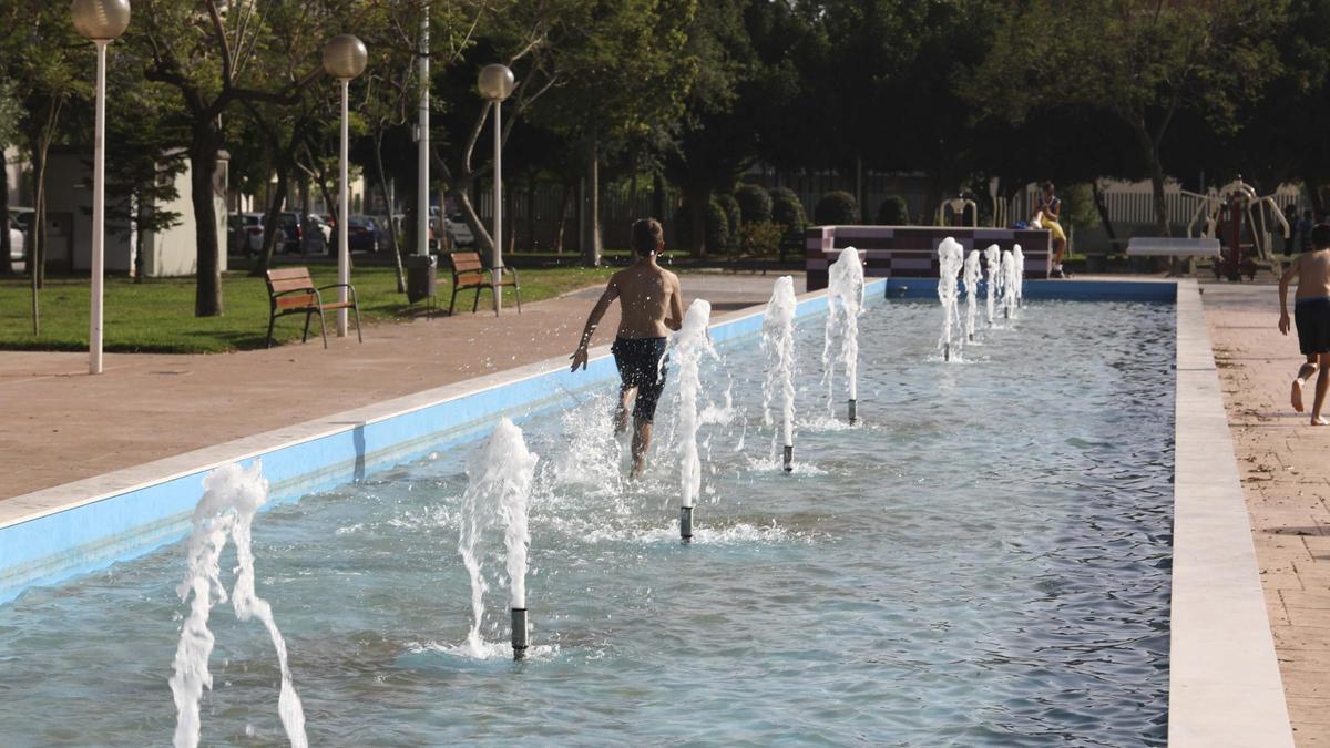 Un niño se refresca corriendo dentro de la fuente ornamental existente en el parque de la Mayorazga.