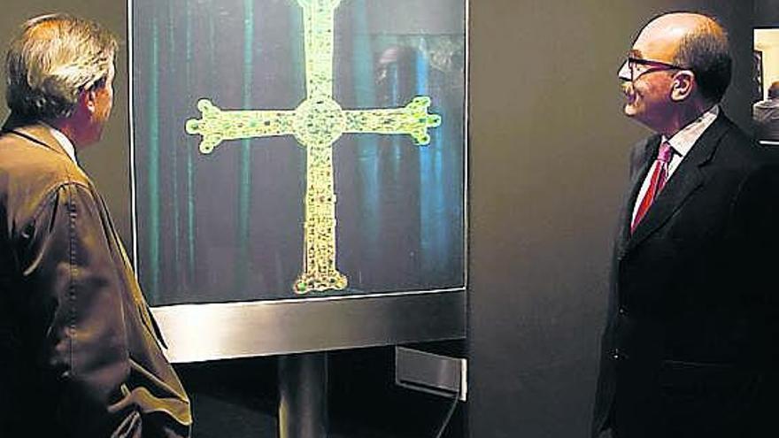 Álvaro Muñiz y César Menéndez observan la imagen holográfica de la Cruz de la Victoria en el pabellón de Cajastur.