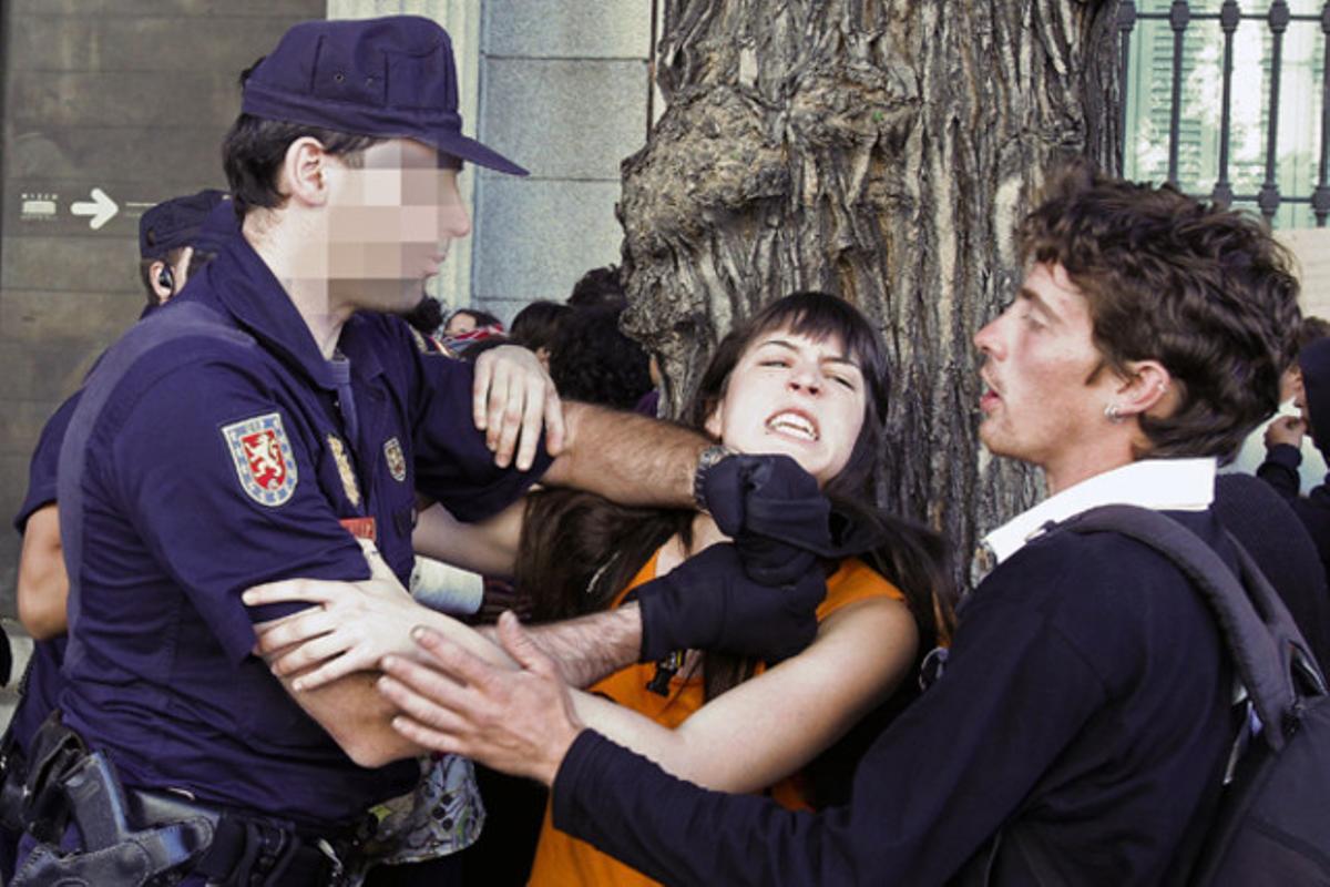 Un policia forceja amb membres del col·lectiu dels indignats concentrats a les proximitats del Congrés dels Diputats