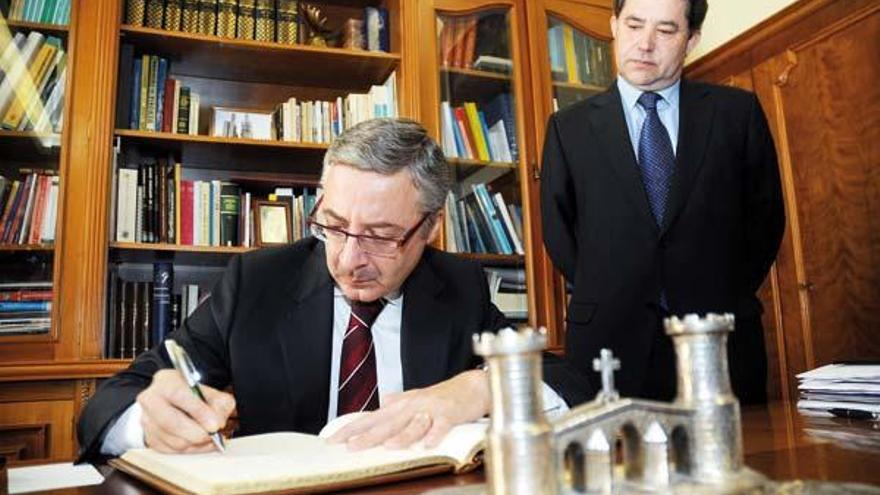 El ministro firma en el libro de honor del Concello, ante la mirada del alcalde Lores.