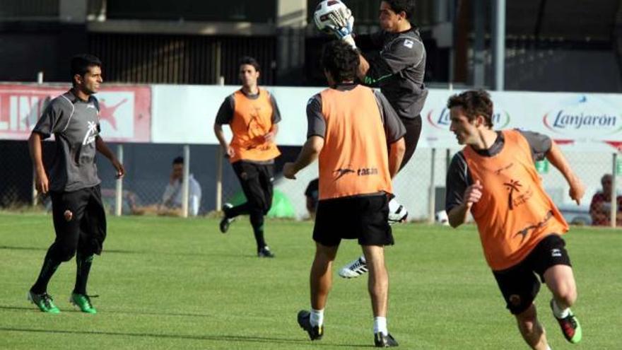 El meta Jaime atrapando un balón en un entrenamiento con Ángel muy atento.