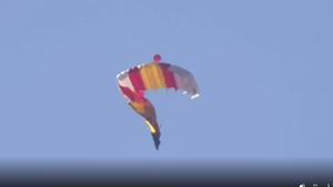 La bandera de España se enrolla en una pierna de uno de los paracaidistas durante su salto en el desfile militar del Día de la Hispanidad