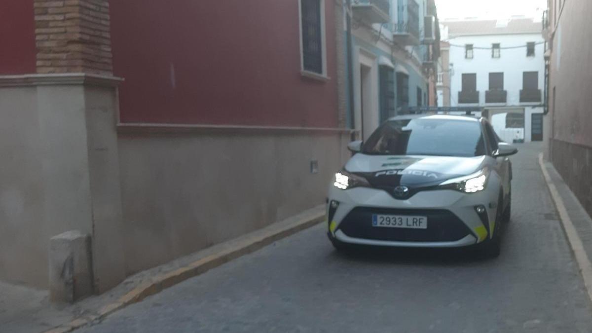 Un coche de la Policía Local de Puente Genil en la calle donde se encuentra la vivienda de la víctima.