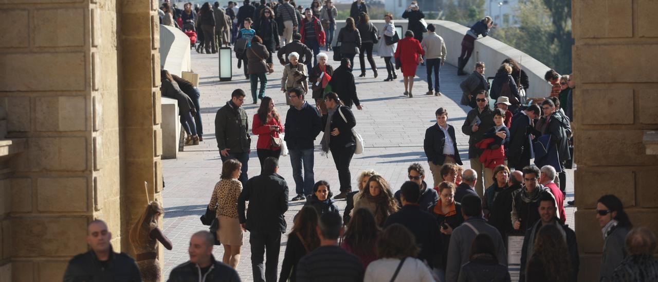 Decenas de personas caminan por el Puente Romano de Córdoba.