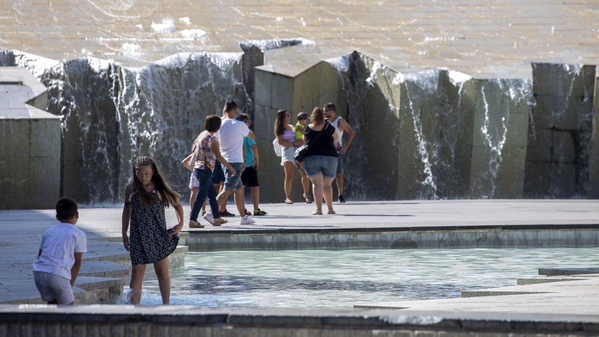 Varias personas se refrescan en la fuente de la Plaza del Pilar.