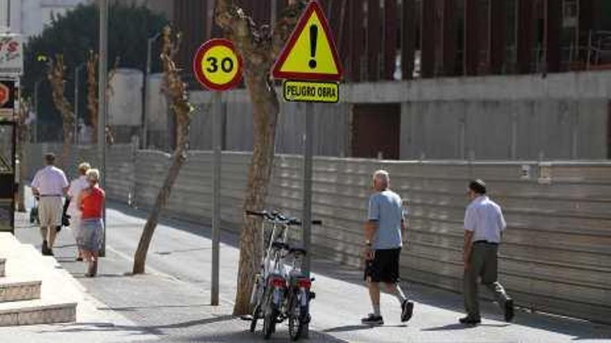 Turistas pasean junto a la obra paralizada.