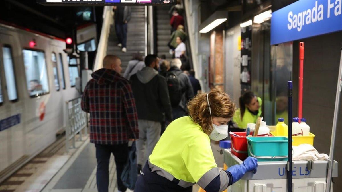 Una operaria de la limpiea con mascarllla trabaja en la estación de metro de Sagrada Família