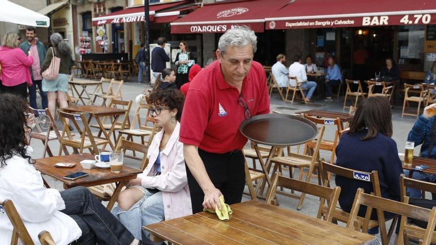 Enrique Valcarce limpia una de las mesas de la terraza de su negocio, en la plaza del Marqués. | Marcos León