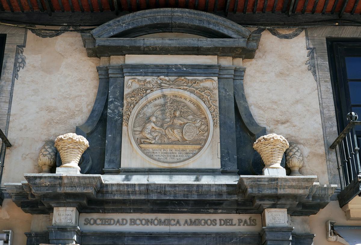 Medallón de mármol blanco del Montepío de Cosecheros y un llamativo lema en español: ‘Socorre al diligente, niega al perezoso’.