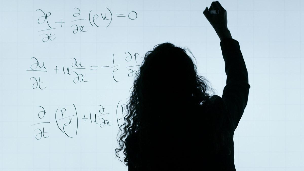 Una mujer escribe en una pizarra fórmulas matemáticas.