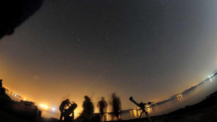 Varios ciudadanos observan estrellas desde una playa gallega.