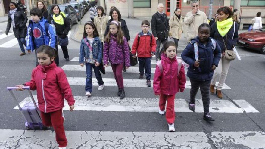 Los alumnos y sus monitores cruzan en un paso de peatones en dirección al colegio a primera hora de la mañana de ayer. / carlos pardellas