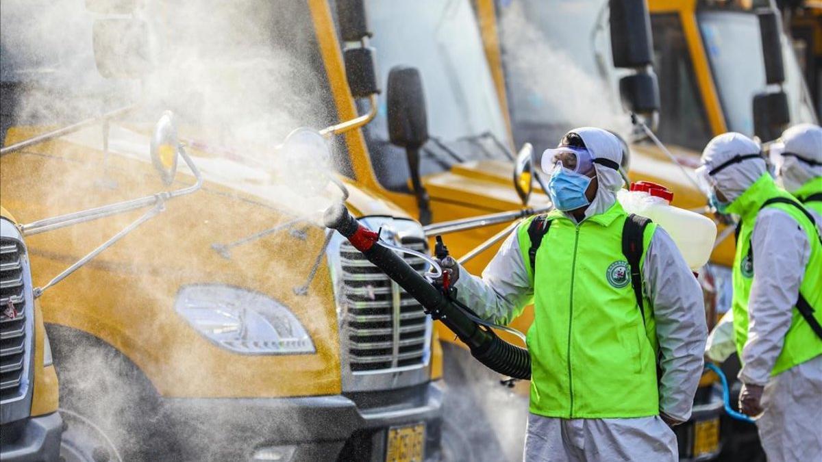 Voluntarios desinfectan autobuses escolares en Tengzhou, China