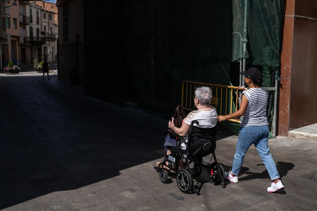 Una mujer trabaja como cuidadora de una anciana en el centro del pueblo.